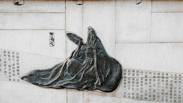 Intricate stone relief depicting Chinese historical figures in Nanjing, China.