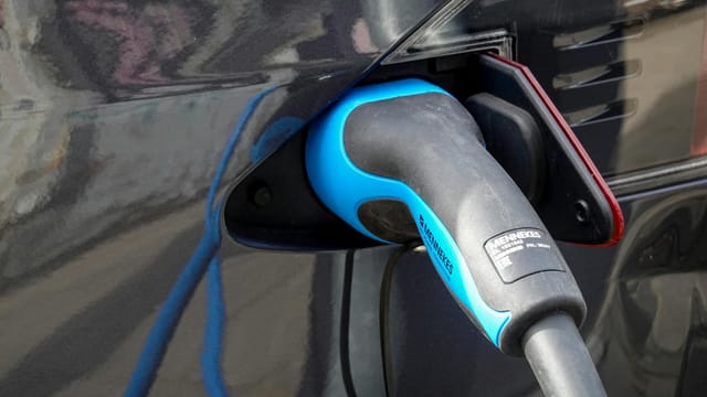 Close-up of an electric vehicle being charged using a Mennekes EV connector.