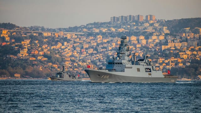 Turkish Navy warships navigate the Bosporus during a sunny day with Istanbul's skyline in the background.