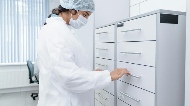 A medical professional in a lab coat organizes files in a sterile clinic environment, focusing on healthcare organization.