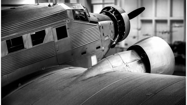 Detailed black and white shot of a classic propeller aircraft engine and fuselage.