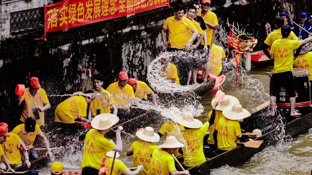 Vibrant dragon boat festival race with colorful teams splashing on the river.