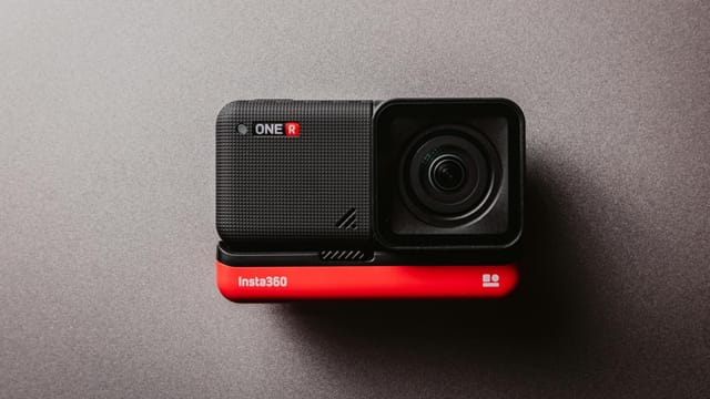 High-quality flat lay of Insta360 ONE R action camera against a gray backdrop, showcasing its sleek design.