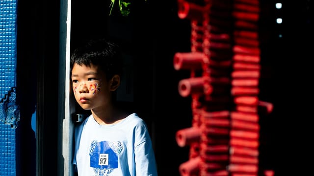 A child in vibrant light during Chinese New Year celebrations in Panama City's Chinatown.