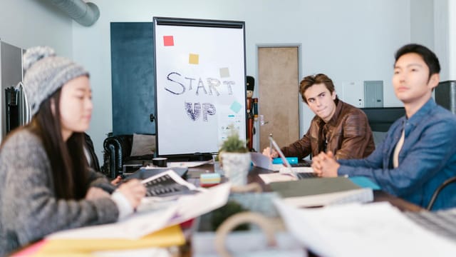 A group of young professionals brainstorming ideas in a startup office setting.