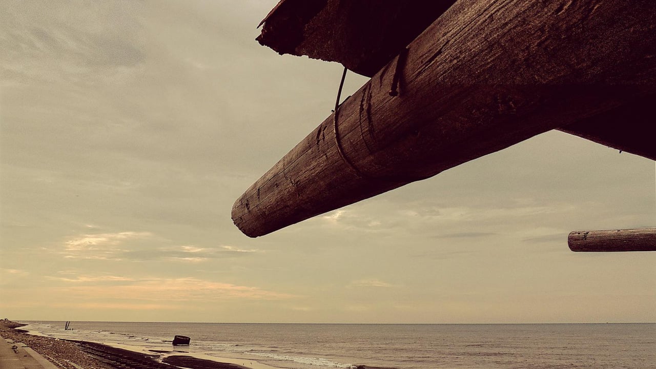 Rustic wooden beams frame a serene sea view at sunset on a Taiwanese beach.