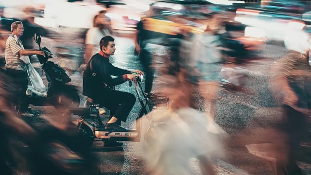Blurred night traffic and motorcyclists in bustling Beijing street.