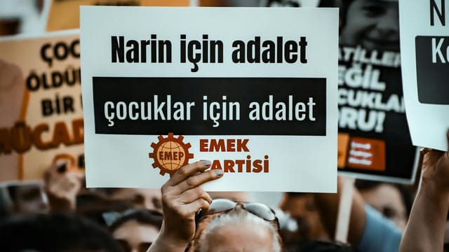 A crowd holds signs advocating for justice and children's rights at a protest.