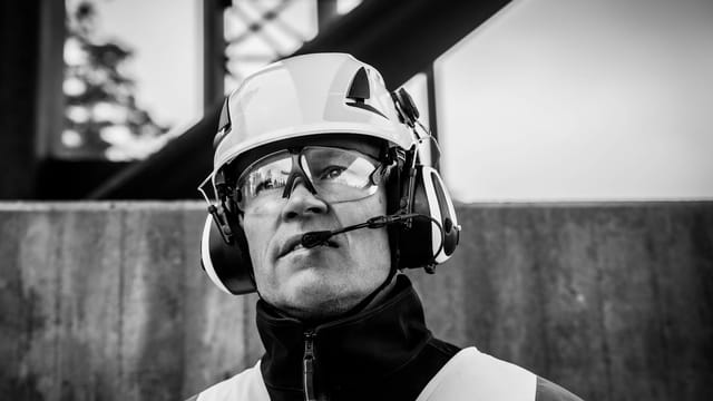 Black and white portrait of a construction worker wearing protective gear and helmet.