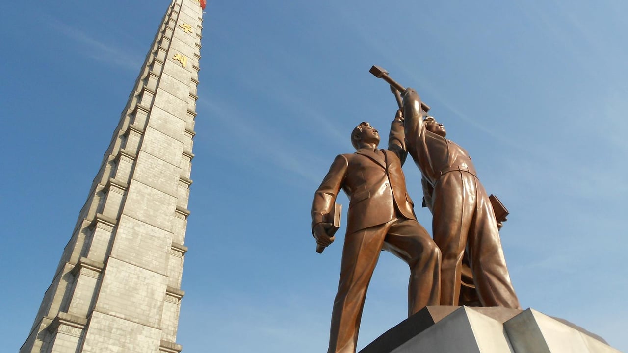 Low angle view of Juche Tower and worker statues against a clear blue sky in Pyongyang, North Korea.