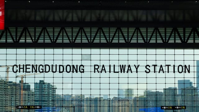 A view from inside Chengdu East Railway Station showcasing the city skyline through large glass windows.