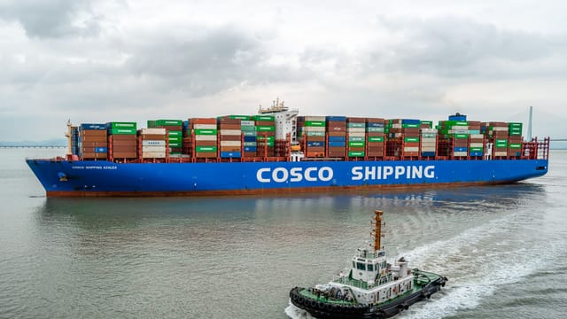 A large COSCO container ship navigates the waters of Ningbo Harbor, China.