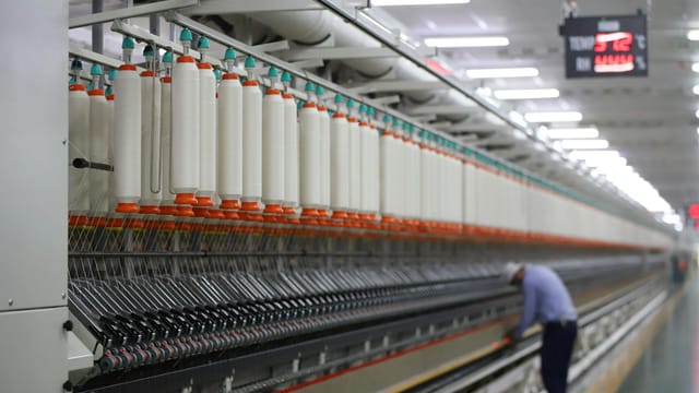 A textile factory in India showcasing modern spinning machinery with a worker.