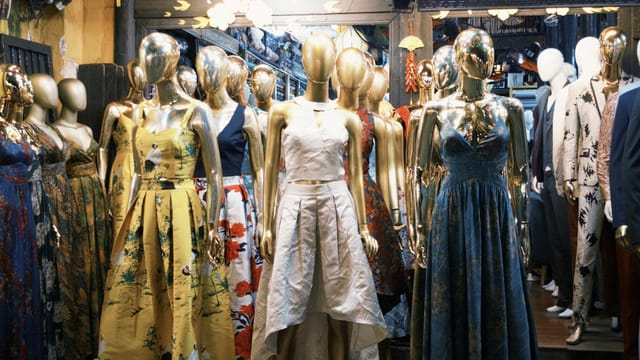 Gold mannequins in colorful gowns at a boutique evoke chic fashion vibes.