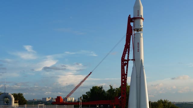 Vostok rocket stands poised on launch pad under clear blue sky at space center.