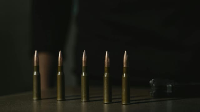 Close-up shot of a row of bullets on a dark surface, emphasizing their metallic texture.
