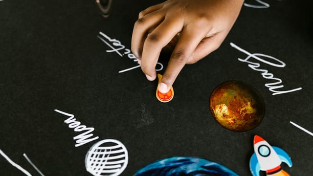 Close-up of a child's hand interacting with a solar system model for a school project.