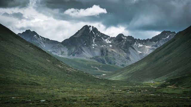 Stunning view of a remote mountain range under dramatic cloudy sky, perfect for nature lovers.