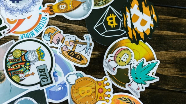 Colorful stickers featuring Bitcoin and cryptocurrency themes on a wooden surface.