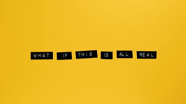 Minimalist text on vibrant yellow backdrop reading 'What if this is all real.'