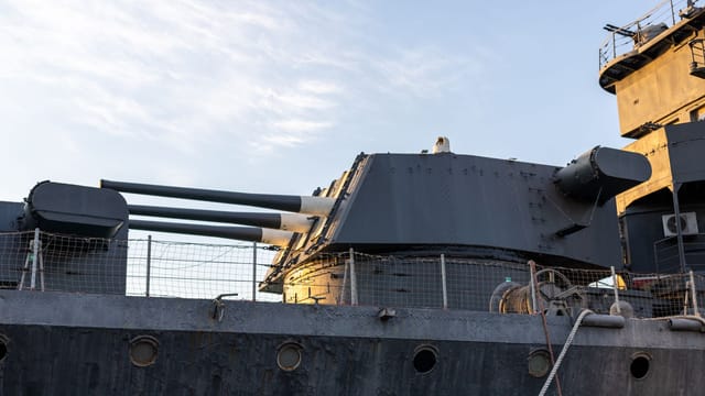 A detailed view of naval ship artillery under the evening sky, highlighting its structure and design.