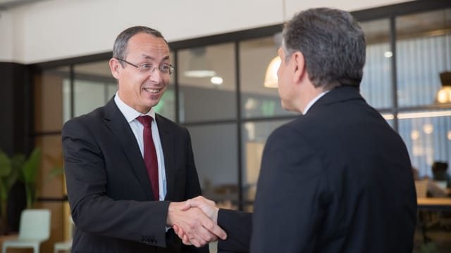Two businessmen in suits shaking hands, symbolizing a successful business deal.