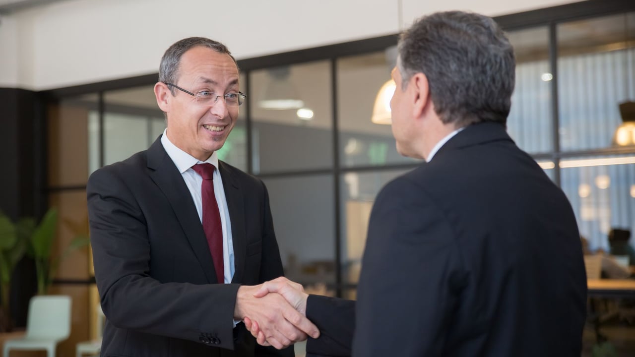 Two businessmen in suits shaking hands, symbolizing a successful business deal.