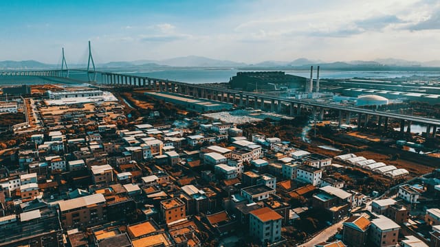 Aerial view of urban sprawl and bridge in Xiamen, Fujian, with distant mountains.