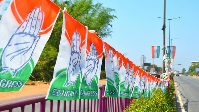 Congress party flags hanging on a roadside railing in Mangaluru, India, symbolizing political promotion.
