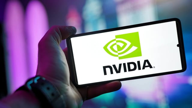 Close-up of a hand holding a smartphone showing the NVIDIA logo on screen with a blurred background.