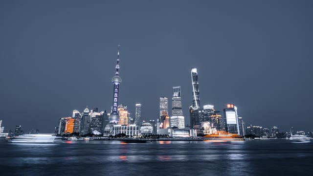 Dramatic night view of Shanghai's skyline featuring iconic skyscrapers and reflections on the Huangpu River.