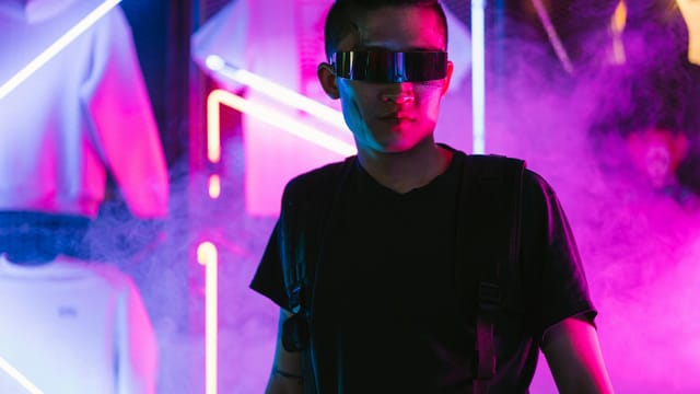 Futuristic man in neon-lit environment wearing sunglasses, exuding cyberpunk style.