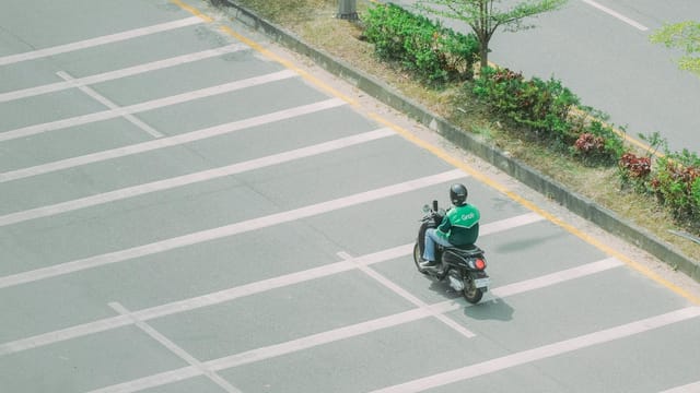 A Grab motorbike rider on a quiet street captured from above, symbolizing urban mobility.