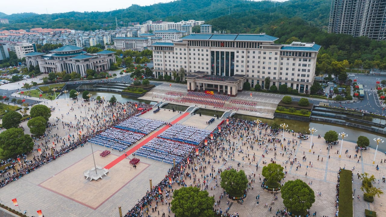 Aerial shot of a massive public gathering in a city square with buildings in background.