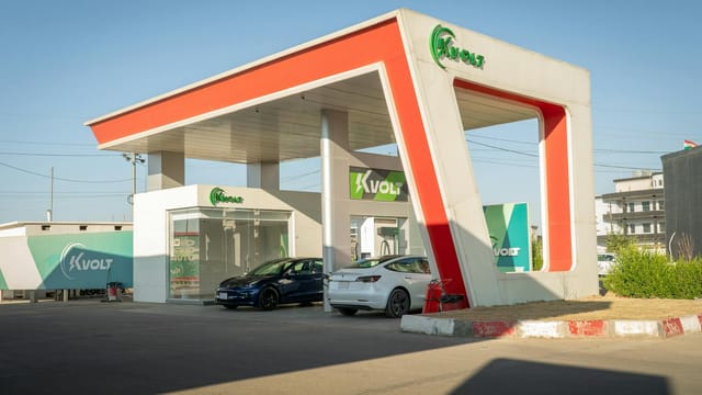 A futuristic electric vehicle charging station featuring Tesla cars under a bright blue sky.