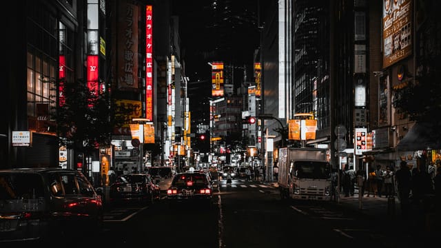 Experience the vibrant nightlife of Tokyo's bustling streets with illuminated signs and pedestrians.