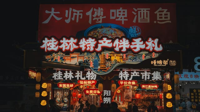 Vibrant scene at a night market in Guilin showcasing illuminated signs and local products.