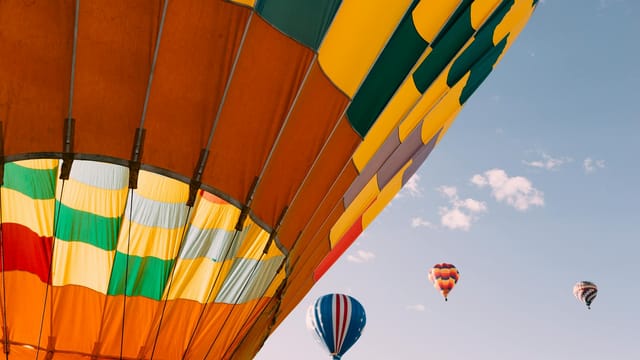 Colorful hot air balloons soaring in the clear blue sky during a festival in Colorado Springs.