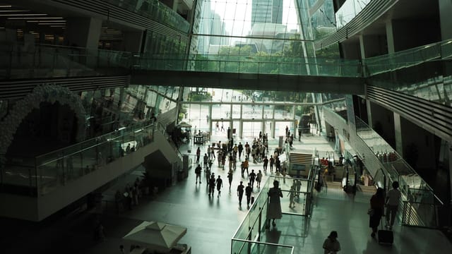 Spacious shopping mall atrium filled with people and natural light.