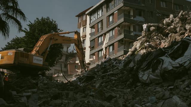 Excavator removing rubble from a collapsed building area in Antakya, Türkiye.