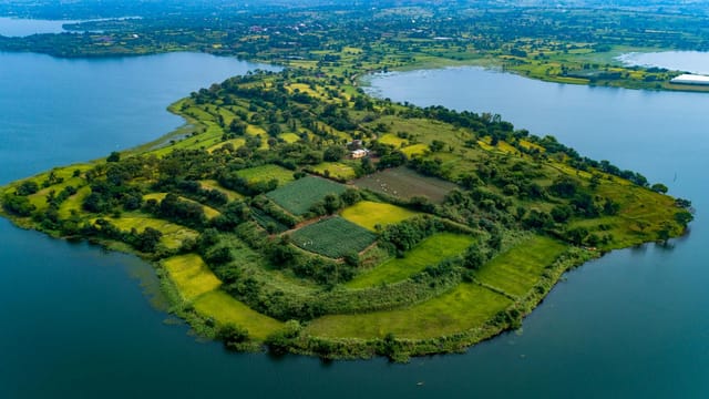Stunning aerial photo of lush green island in Igatpuri, India surrounded by blue waters.