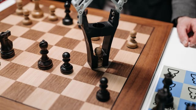Robotic arm playing a strategic chess game on a wooden board, showcasing technology and innovation.