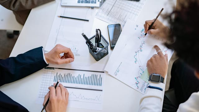 Business team analyzing financial charts and graphs during a collaborative meeting.