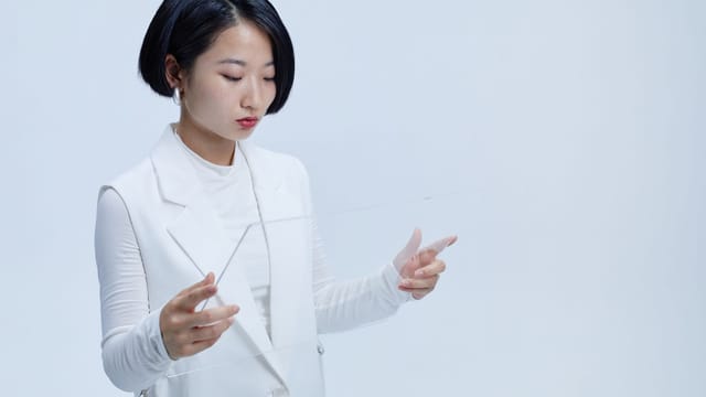 Young woman interacting with a futuristic transparent screen, showcasing modern technology concepts.
