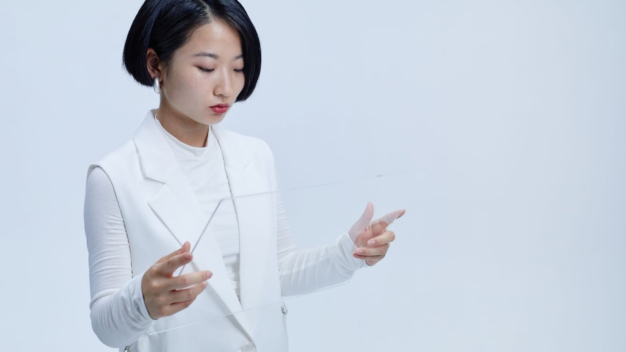 Young woman interacting with a futuristic transparent screen, showcasing modern technology concepts.