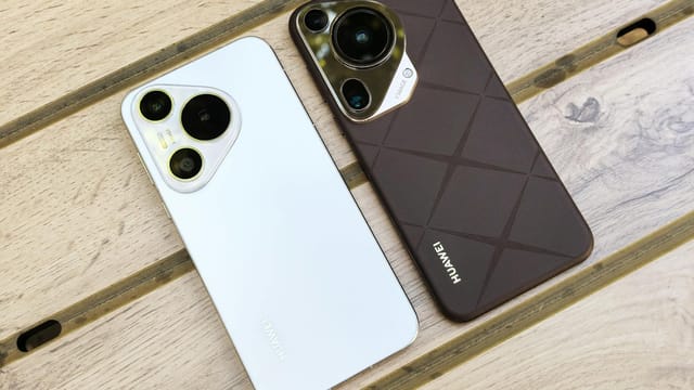 Two Huawei smartphones with sleek designs placed on a wooden table enhance the modern tech aesthetic.