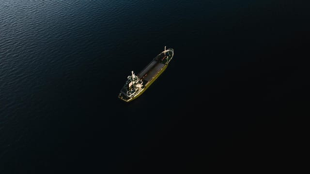 Drone shot of a lone vessel navigating the dark blue waters off Okinawa, Japan.