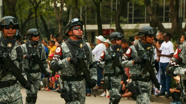 A military parade showcasing armed forces in uniform and tactical gear, marching in formation.