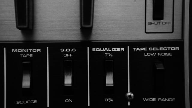 Black and white close-up of an audio control panel featuring an equalizer and switches.