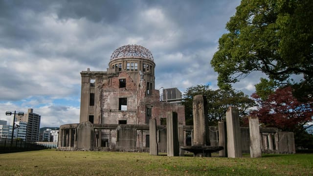 The iconic Hiroshima Peace Memorial Dome against a cloudy sky in Hiroshima, Japan.